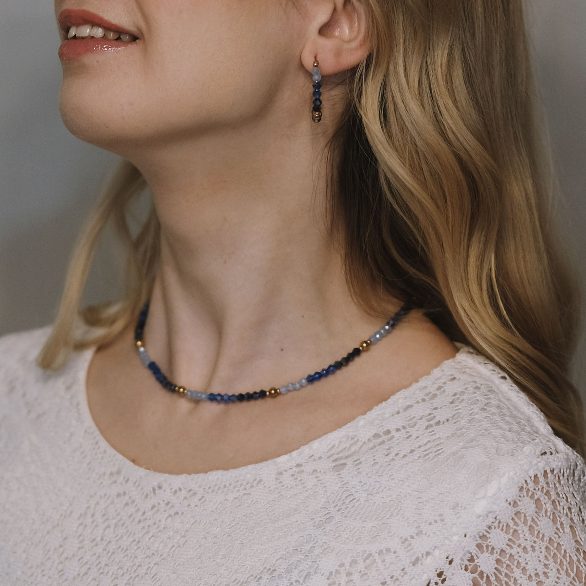 Elegantti Jolie Sapphire -kaulakoru, lähikuva sinisten helmien ja kullan sävyisistä yksityiskohdista.